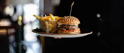 A person holding a plate with a burger and fries.