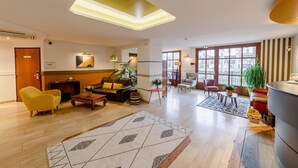Un vestíbulo amplio con diseño moderno, que incluye un área de estar central, una recepción y ventanas grandes que dejan entrar luz natural.