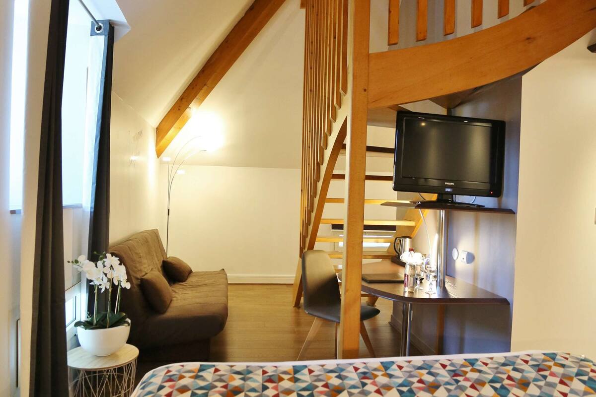 Een slaapkamer met een bed, een televisie, een stoel en een trap.