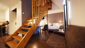 Un interior moderno con una escalera de madera, una cama, un sofá y un comedor.