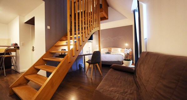 Un intérieur moderne avec un escalier en bois, un lit, un canapé et un coin repas.