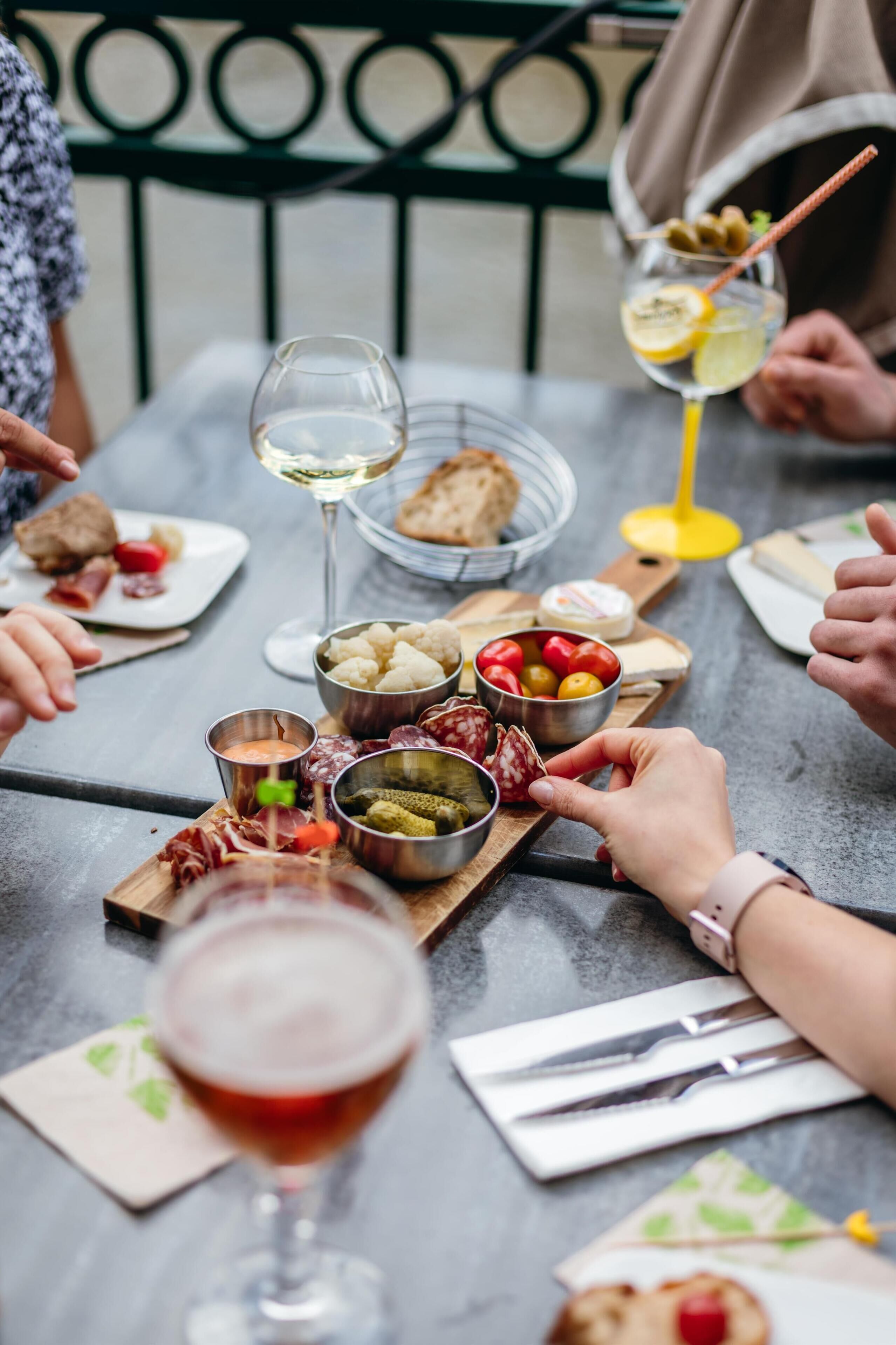 A table set with various cheeses, charcuterie, and a glass of white wine.