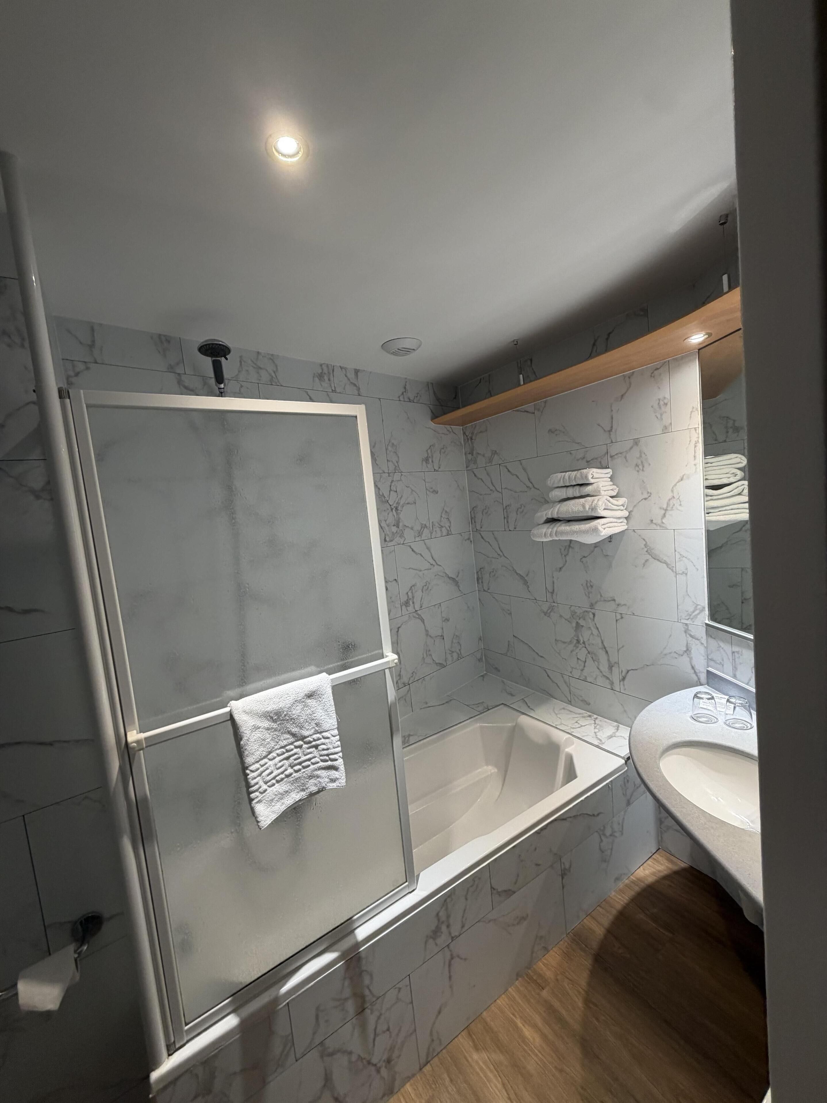 Een moderne badkamer met een douchecabine van glas, een badkuip en een wastafelmeubel met een wastafel.