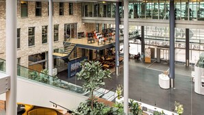 A multi-level atrium with a staircase, seating areas, and a reception desk. - NH Den Haag (The Hague)