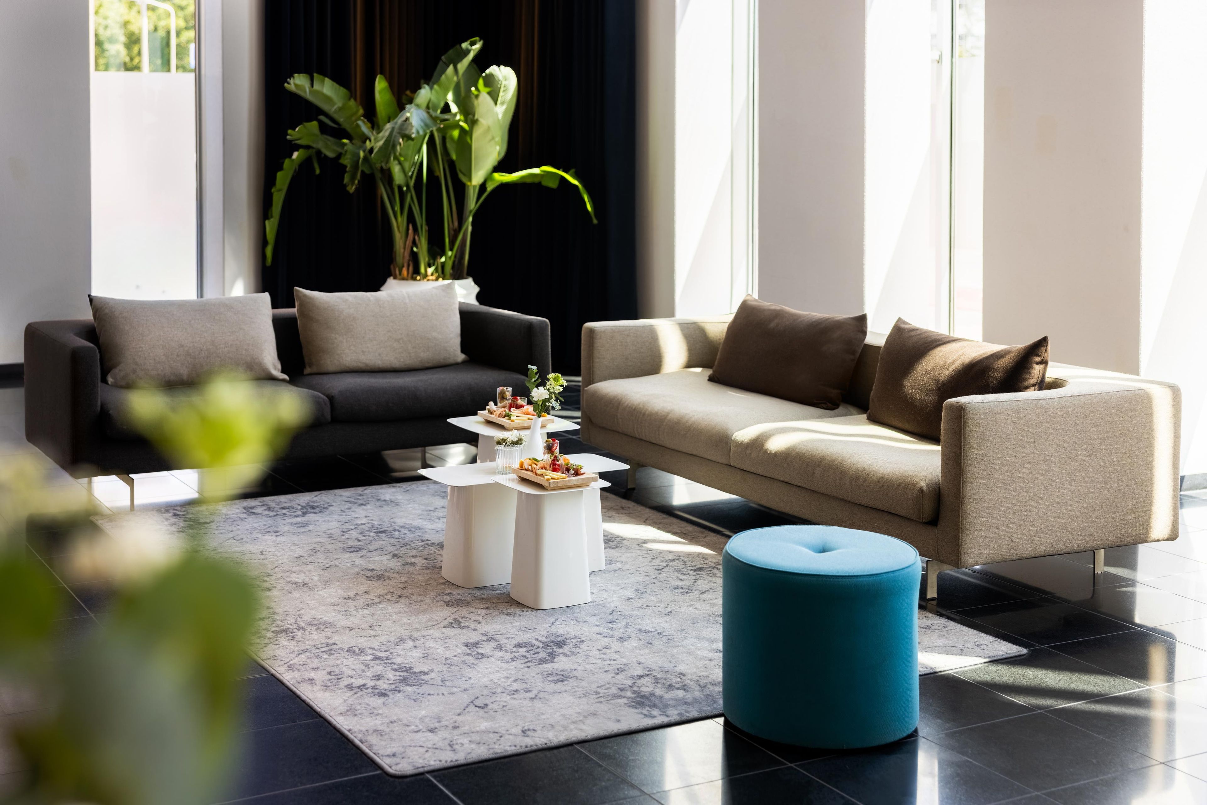 Una sala moderna con dos sofás, una mesa de centro y un pouf azul.