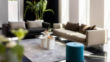 Una sala moderna con dos sofás, una mesa de centro y un pouf azul.