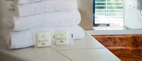 A stack of white towels and two bottles of soap on a white countertop in a bathroom.