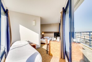 A hotel room with a bed, a desk, and a view of the city. - Brit Hotel Saint Malo - Le Transat (Saint-Malo)