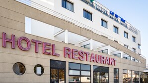 Un hotel con un cartel que dice "HOTEL RESTAURANT" y un cartel visible de "LE TRAVAILLO" encima.