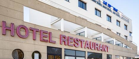 A hotel with a sign reading "HOTEL RESTAURANT" and a visible "LE TRAVAILLO" sign above.