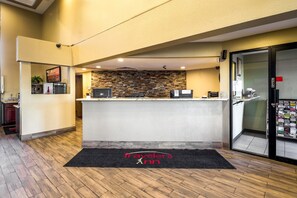 A reception area with a stone wall, a reception desk, and a black doormat with "Travelers Inn" text.