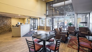 A spacious indoor area with a reception desk, multiple seating arrangements, and large windows offering views of the outside. - Travelers Inn (Phoenix)