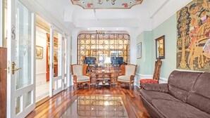 A spacious living room with a brown leather sofa, a glass coffee table, and a decorative partition with a floral pattern. - Cornell Hotel (San Francisco)