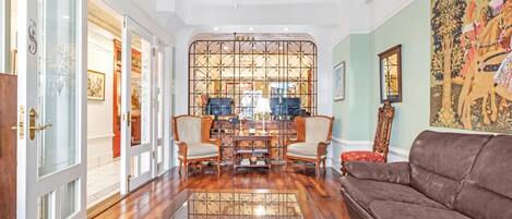 A spacious living room with a brown leather sofa, a glass coffee table, and a decorative partition with a floral pattern.