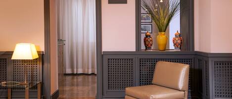 A lobby with a leather chair, a lamp, a bar sign, and decorative vases.