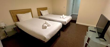 A hotel room with two beds, a TV, and a desk.