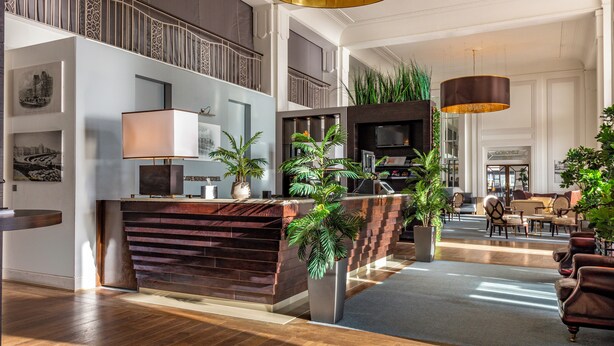 A spacious lobby with a reception desk, seating area, and a staircase leading to an upper level. - Cavendish Hotel (Eastbourne)