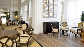 A spacious lobby with multiple seating areas, a fireplace, and a view of the street. - Cavendish Hotel (Eastbourne)