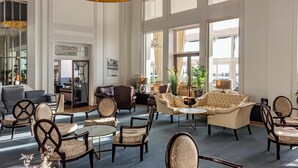A spacious lobby with a mix of seating options including sofas, armchairs, and a bar area. - Cavendish Hotel (Eastbourne)