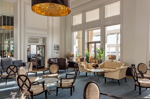 Eine großzügige Lobby mit verschiedenen Sitzgelegenheiten, darunter Sofas, Sessel und eine Bar.