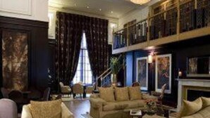A spacious living room with a high ceiling, a chandelier, and a fireplace. - Cavendish Hotel (Eastbourne)