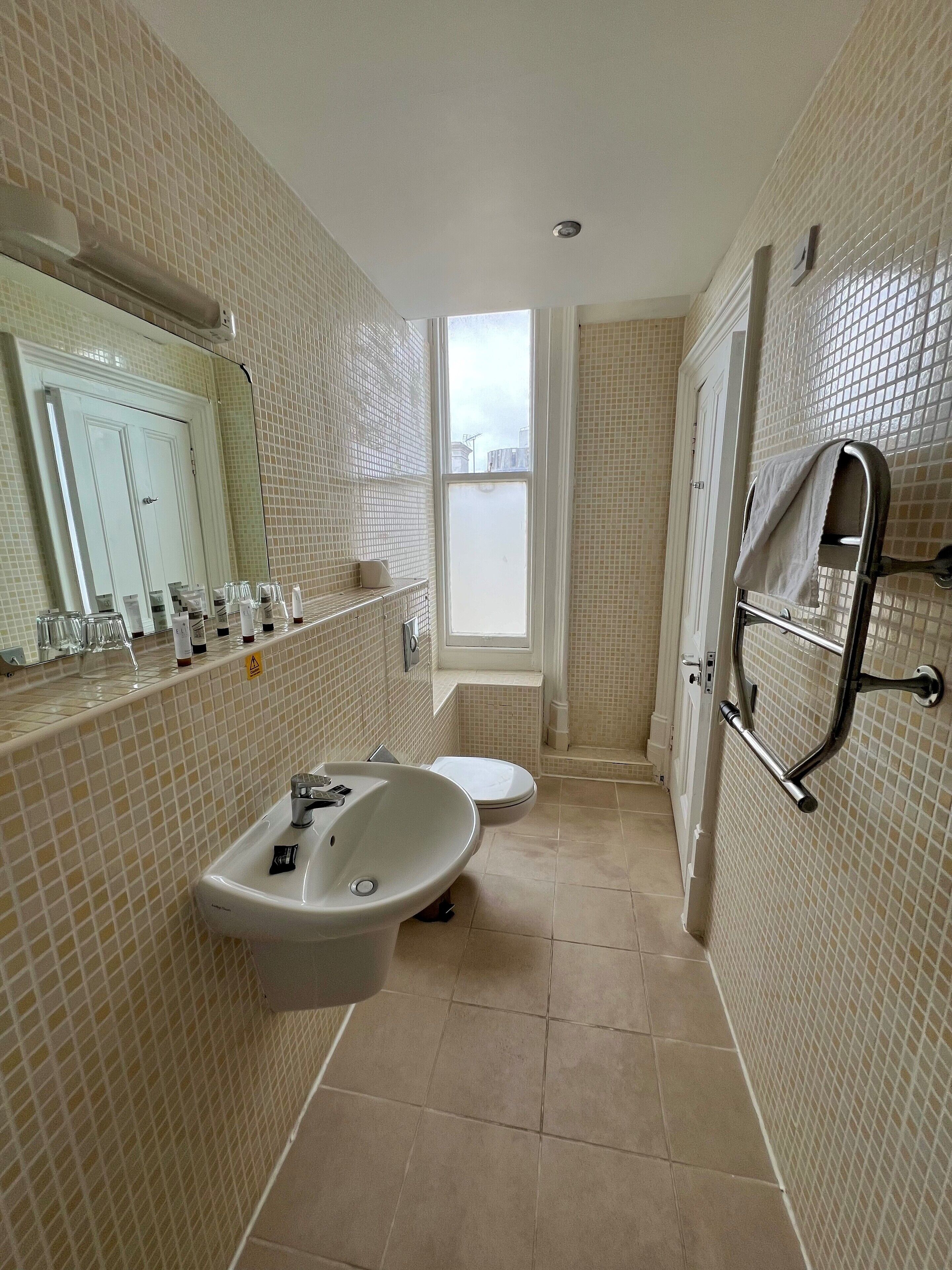 A bathroom with a sink, toilet, and a window.