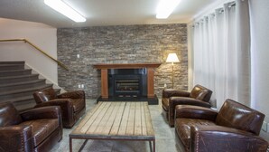 Ein Wohnzimmer mit Steinwand, Kamin, Ledersofas und einer Wendeltreppe.