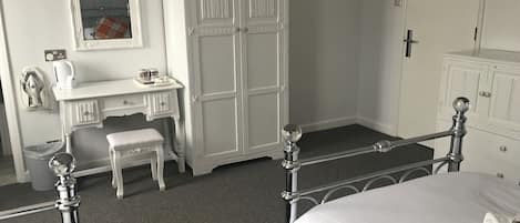 A bedroom with a bed, a desk with a chair, a wardrobe, and a mirror.