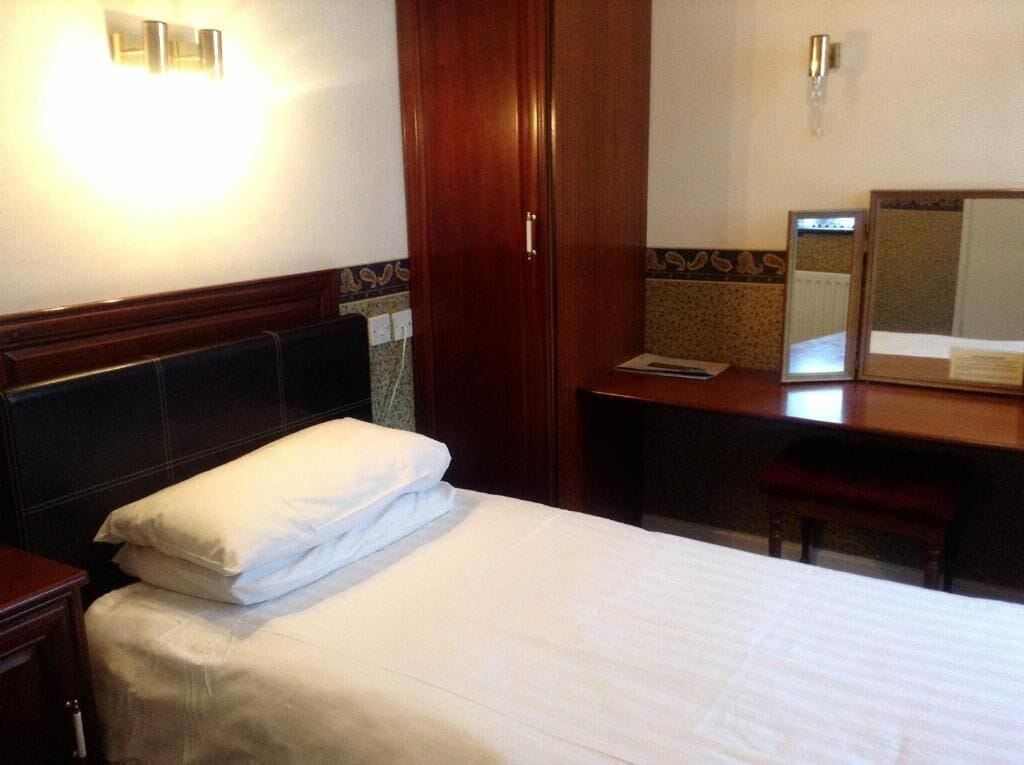 Une chambre d’hôtel avec un lit, un bureau et un miroir.