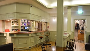 A bar area with stools, a counter, and a television. There are wooden floors and a staircase in the background. - The Star Hotel (Southampton)