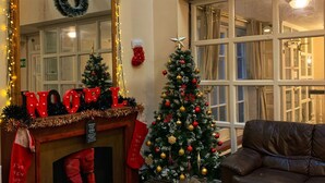 A cozy living room with a fireplace, a Christmas tree, and a large mirror with 'NOEL' decorations. - The Star Hotel (Southampton)