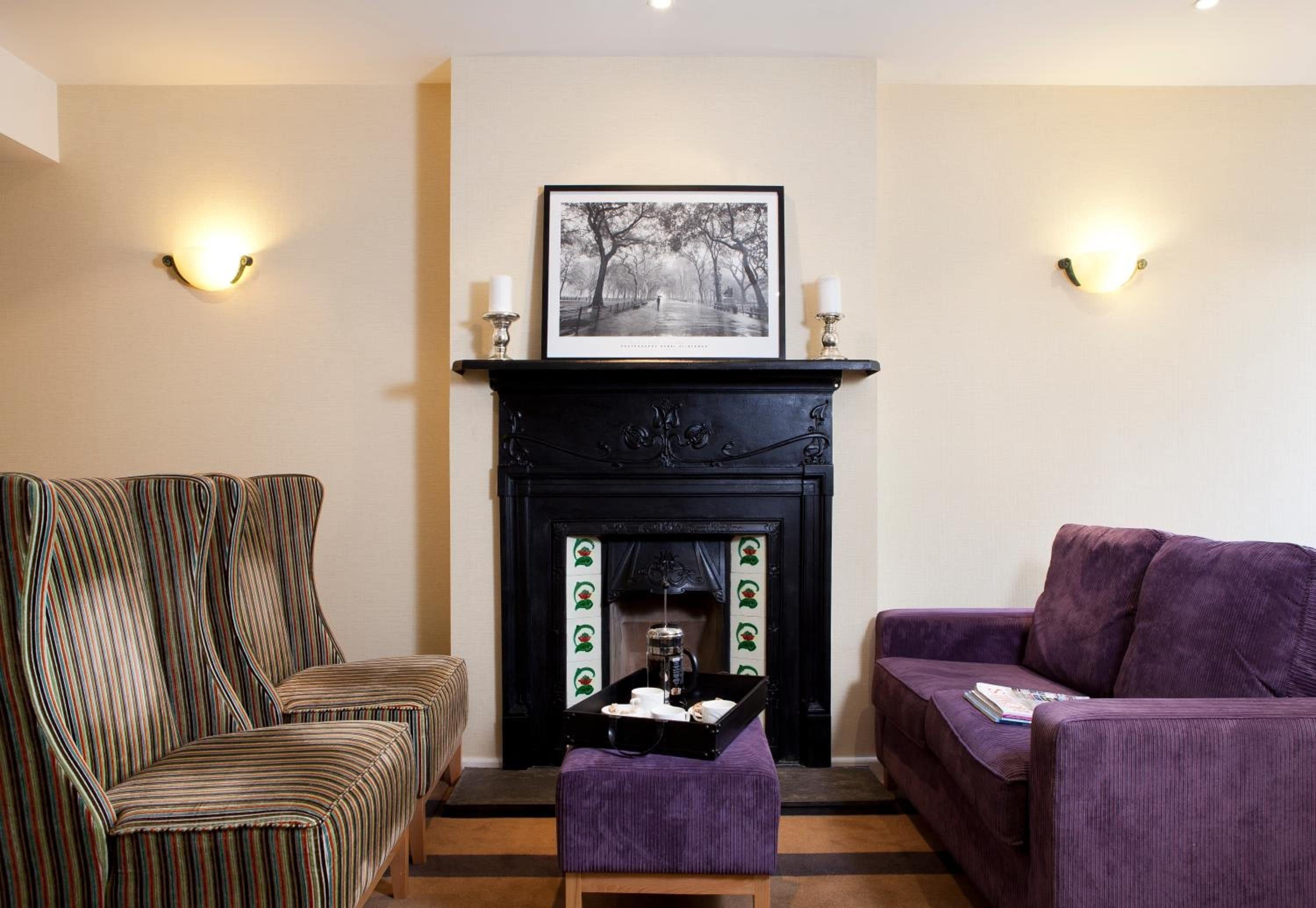 A living room with a fireplace, striped sofas, and wall sconces.