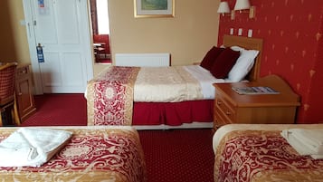 A hotel room with two beds, a wooden nightstand, a dresser, a red carpet, and a painting on the wall.