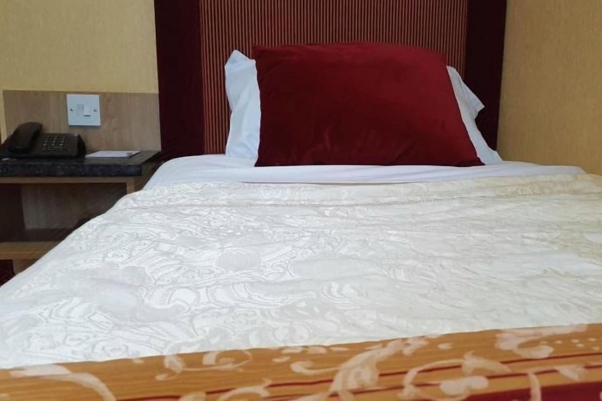 A hotel room with a bed, a nightstand, and a telephone.