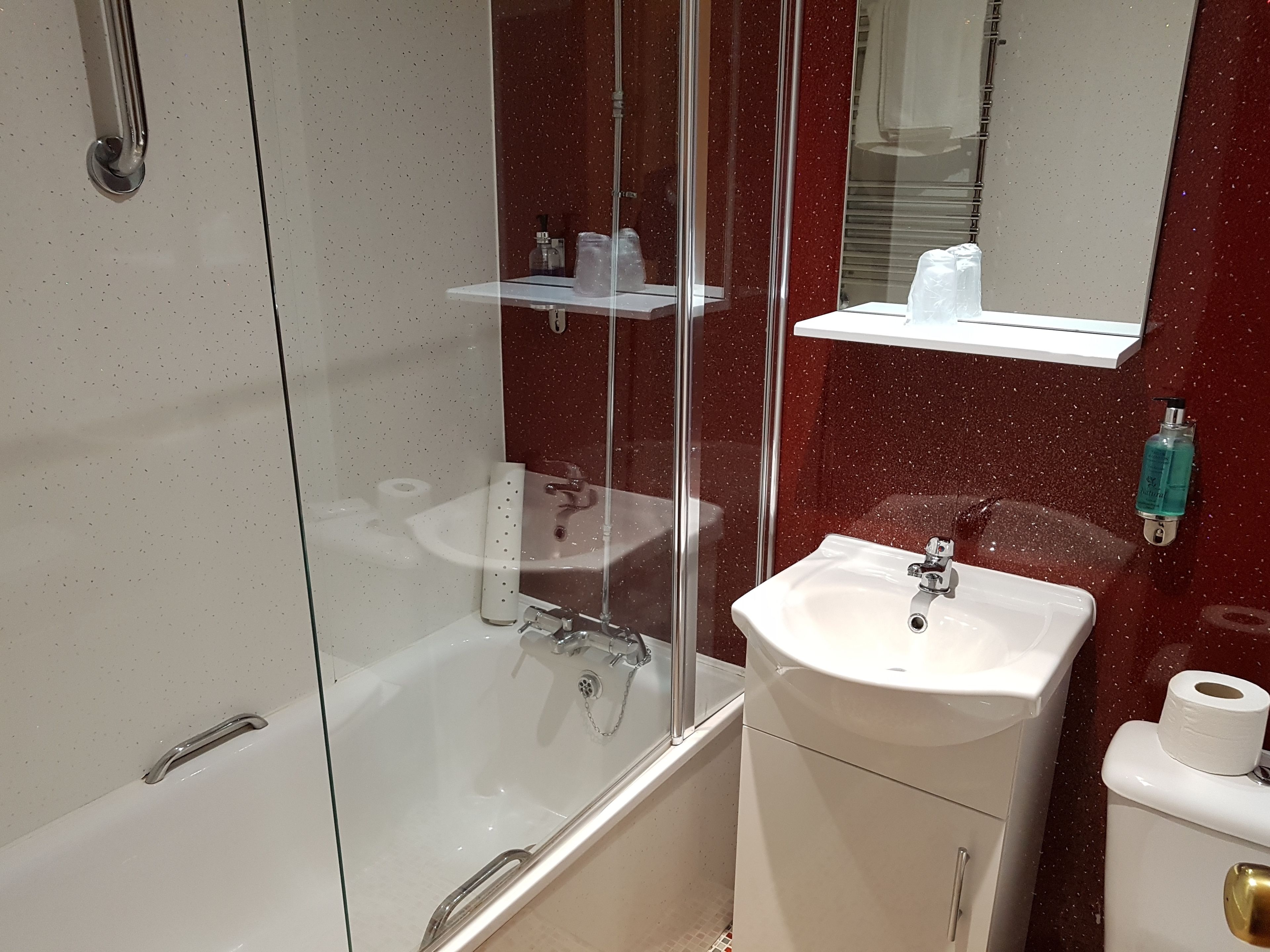 A bathroom with a glass-enclosed shower, a white sink, and a toilet.