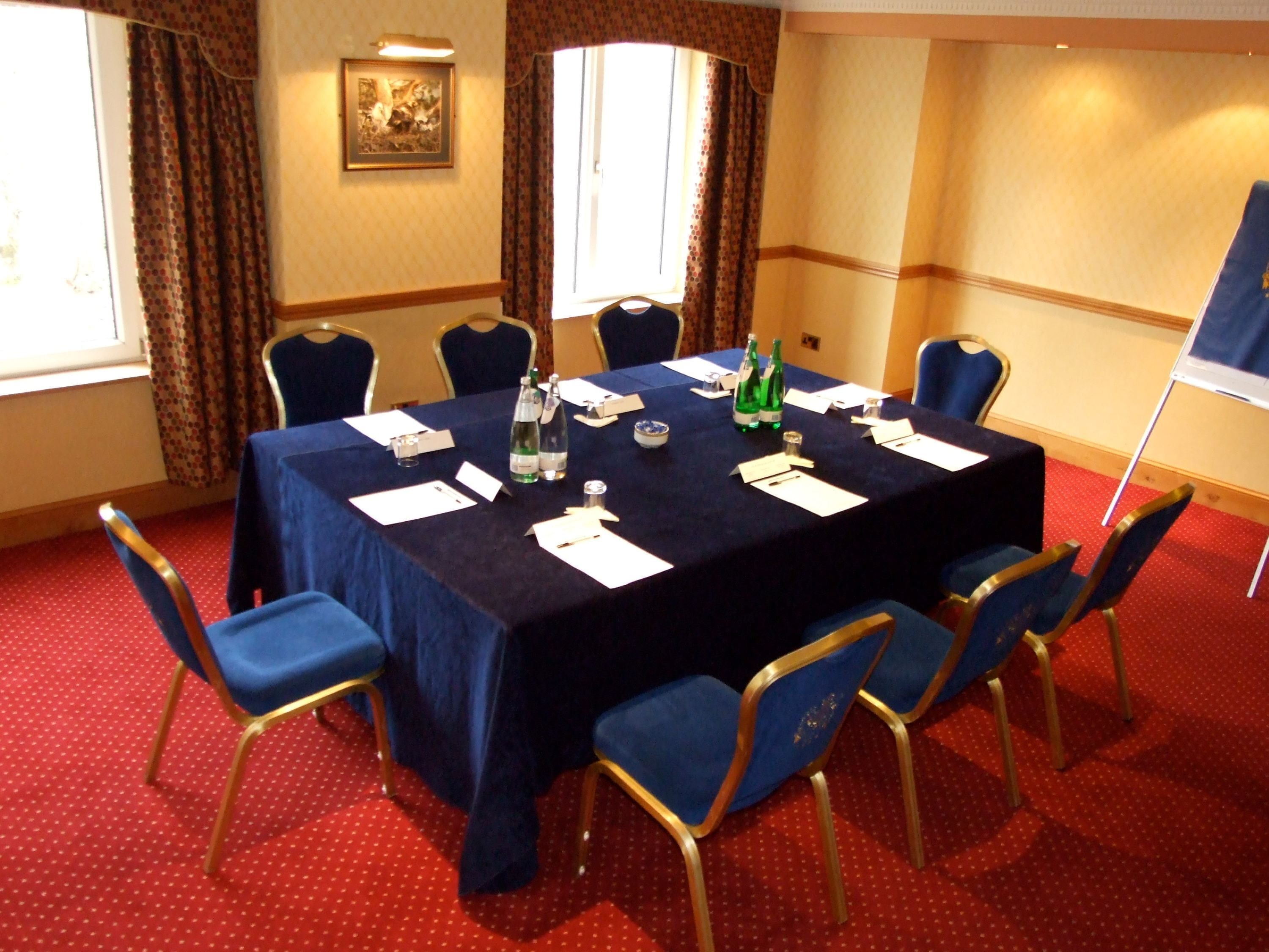 Una sala de conferencias con una mesa azul oscuro, sillas azules y un suelo cubierto de alfombra roja.