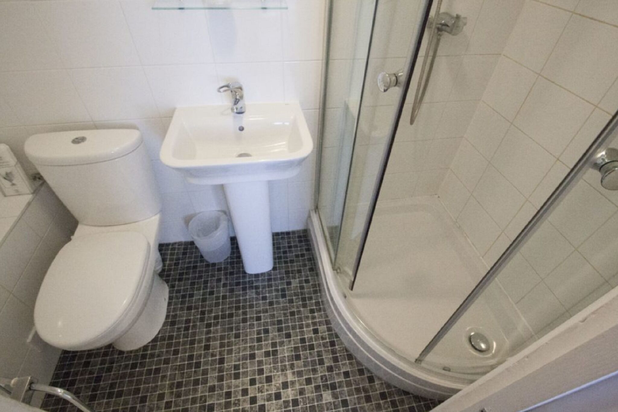 Une salle de bain équipée de toilettes, d’un lavabo et d’une douche à parois en verre.