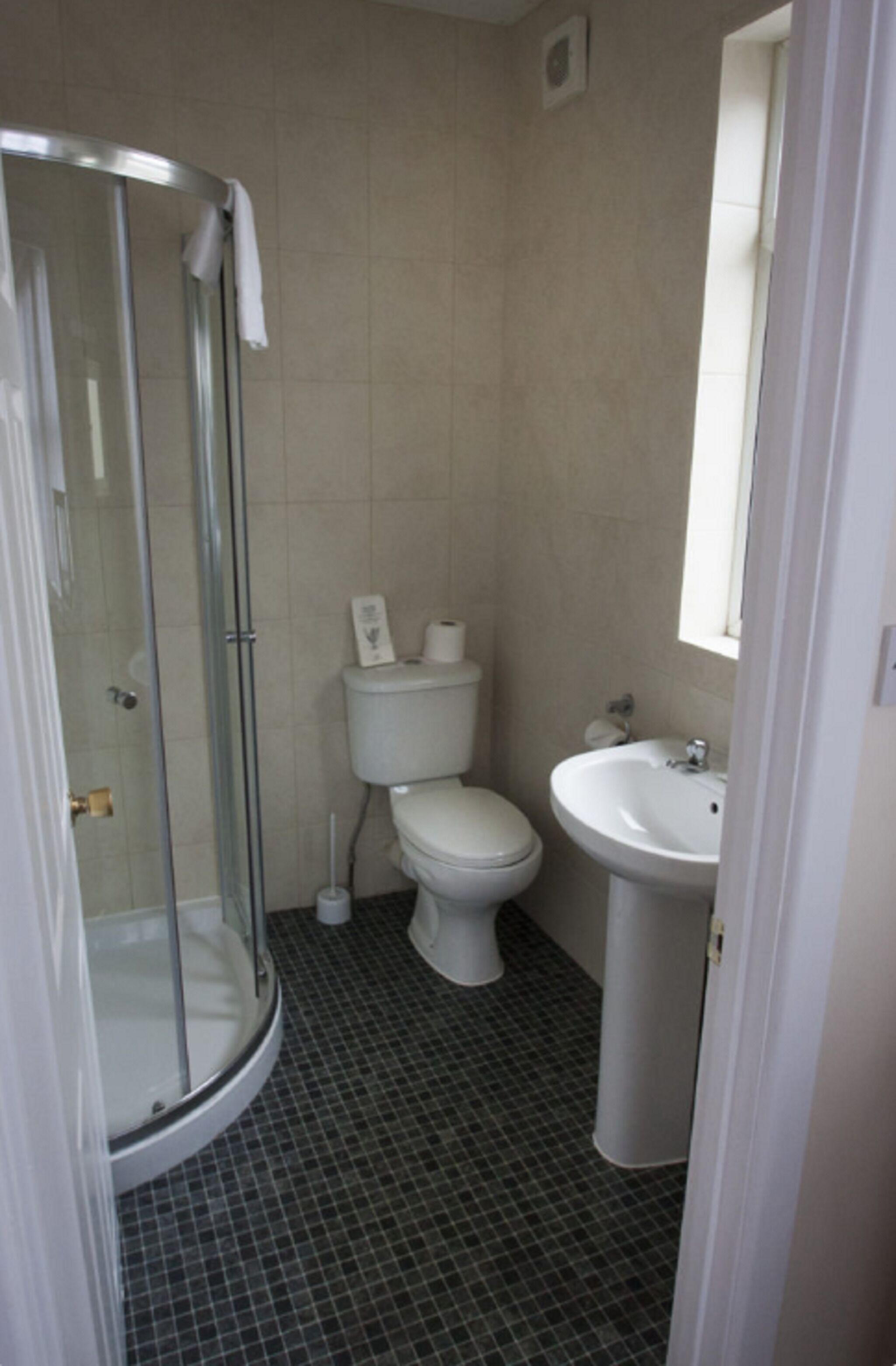 A bathroom with a glass shower enclosure, a toilet, and a sink.
