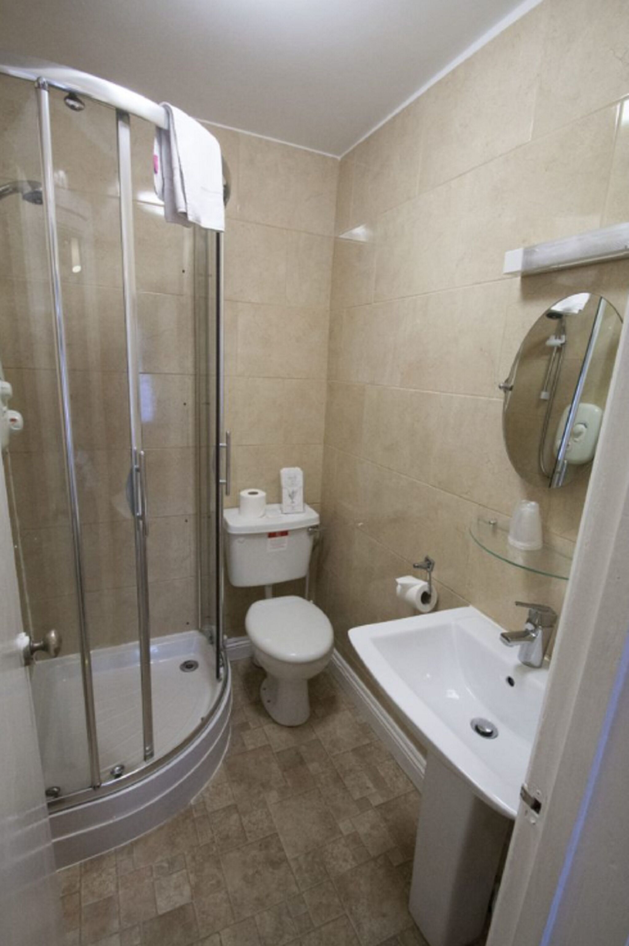 A bathroom with a glass shower enclosure, a toilet, a sink, and a mirror.