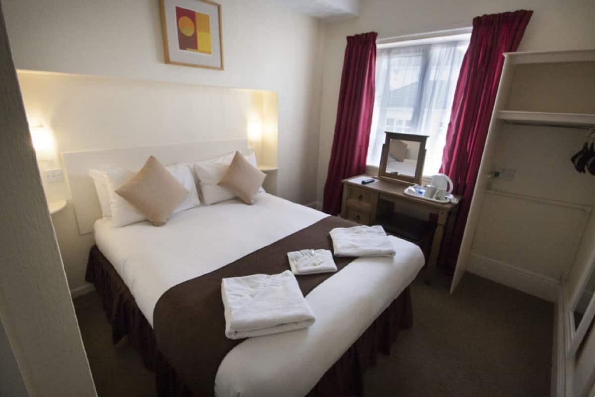 Une chambre d’hôtel comprenant un lit, des tables de chevet, un bureau, un miroir et une armoire.