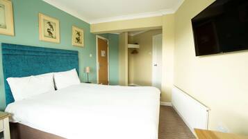 A hotel room with a large bed, a flat-screen TV mounted on the wall, and framed pictures on the wall.