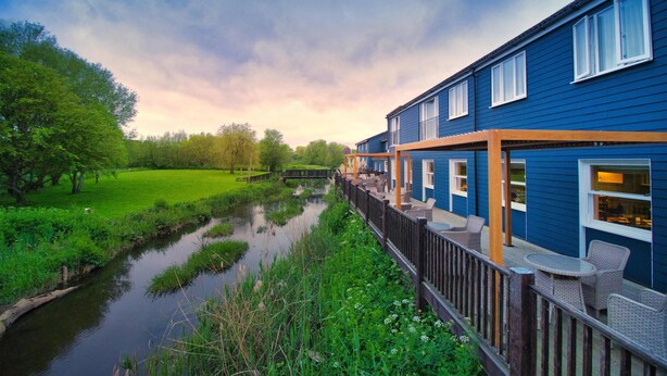 A riverside hotel with outdoor seating and a view of the river.