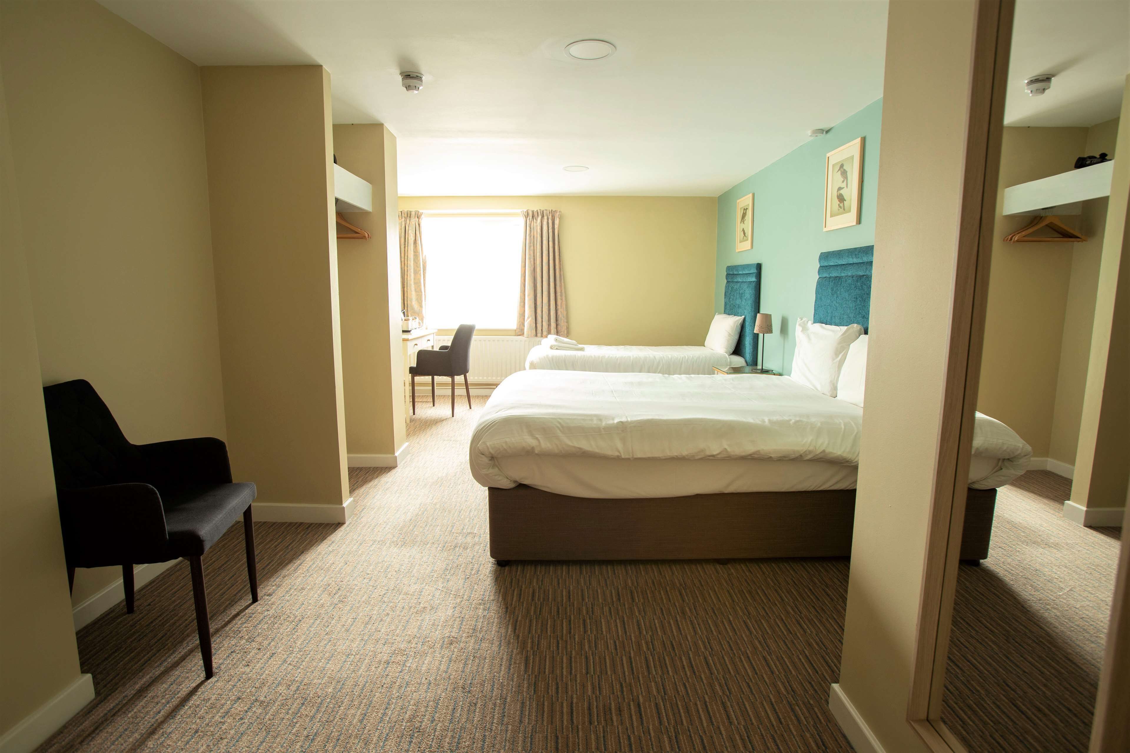 A hotel room with two beds, a desk, and a chair.