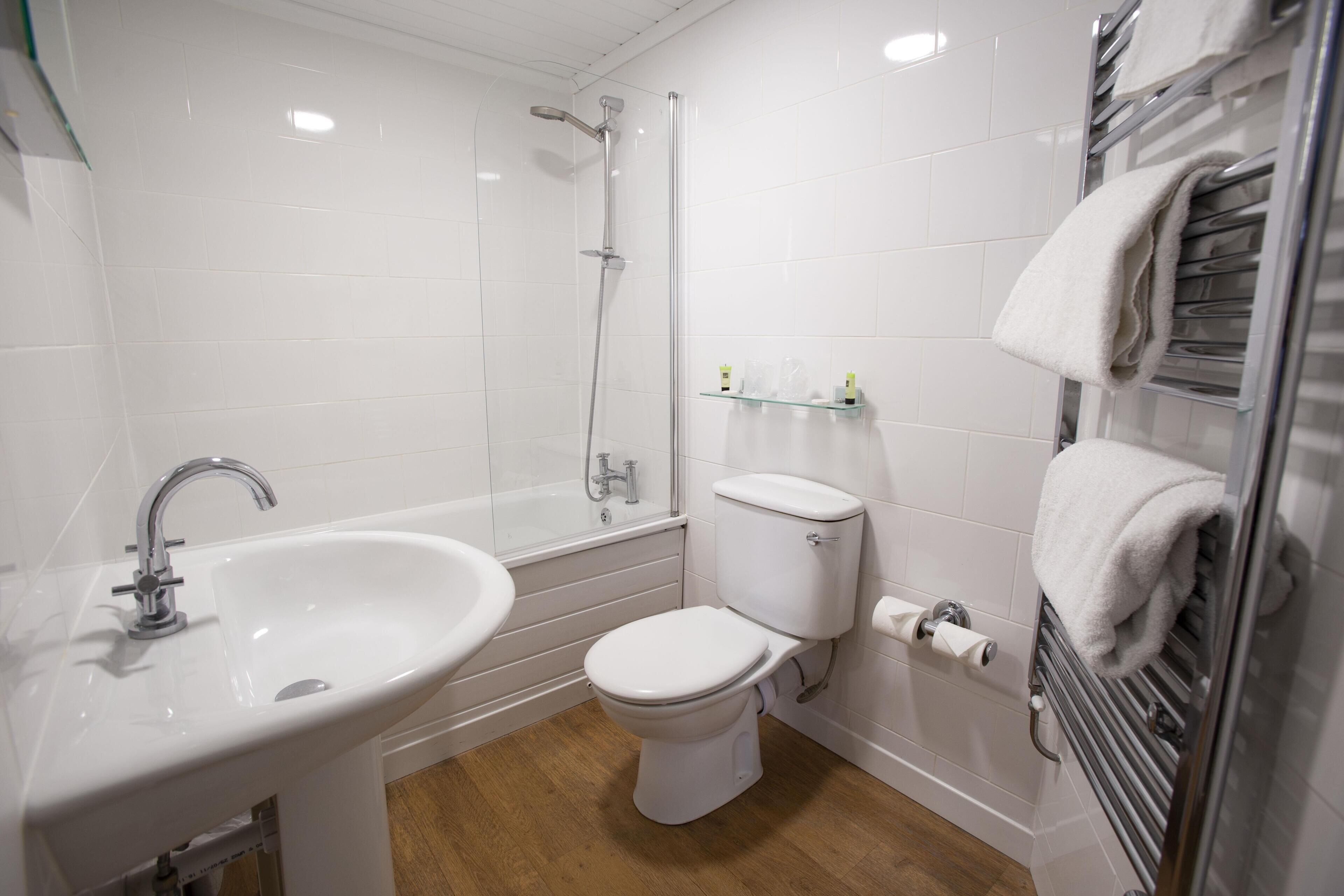 Un baño moderno con lavamanos, inodoro, ducha y toallero.