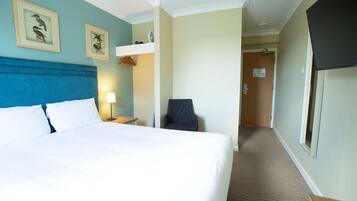 Una habitación de hotel con una cama grande, un escritorio, una silla y un televisor.