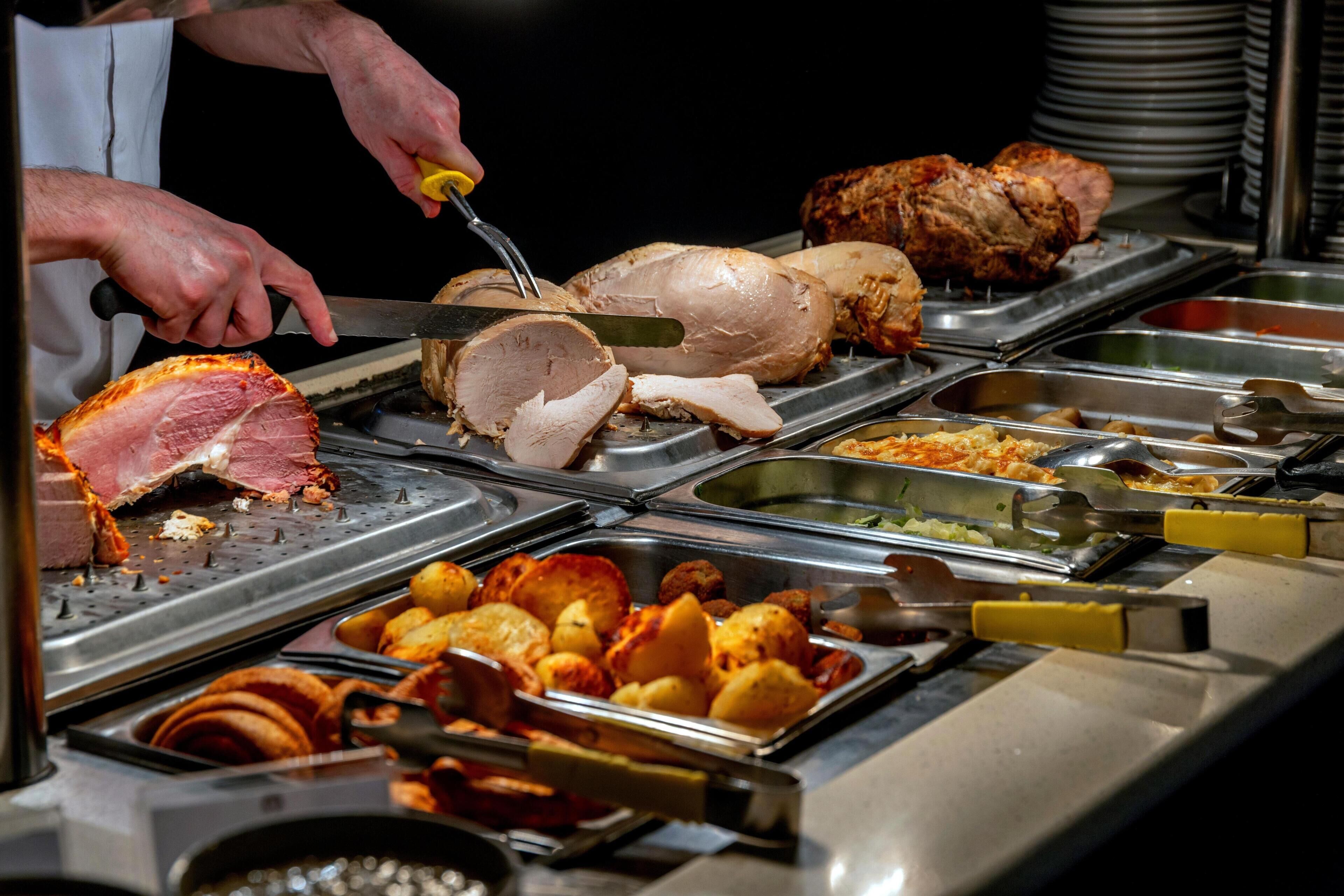 Un bufé con diversos tipos de carne y acompañamientos.