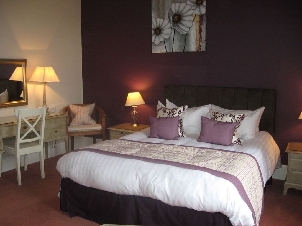 A bedroom with a large bed, two bedside tables, a desk, and a chair.