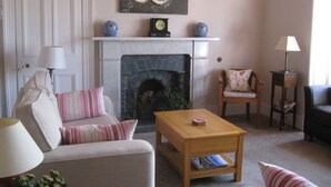 Una sala de estar con chimenea, un sofá, una mesa de centro de madera y una silla.