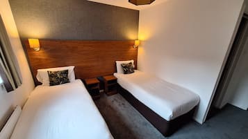 A hotel room with two single beds, a wooden headboard, and bedside lamps.