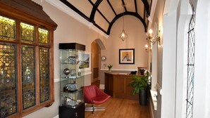 Una habitación con suelo de madera, una silla roja, una vitrina de cristal y un mostrador de recepción de madera.